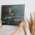 Framed canvas print of impressionist oceanic artwork featuring a bright lighthouse and a red boat in a stormy sea