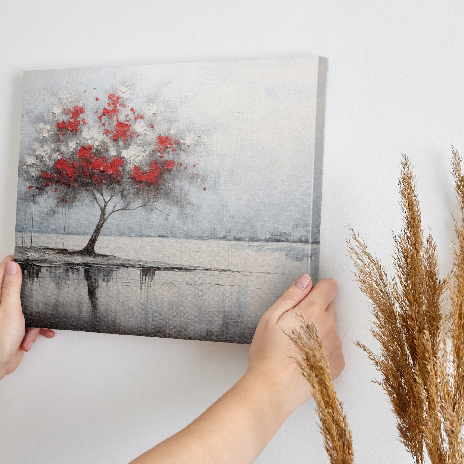 Abstract painting of a lone tree with red and white leaves reflected in water against a grey backdrop