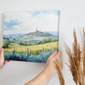 Framed canvas print of a Tuscan landscape with watercolor rolling hills and a village