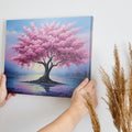 Framed canvas print of a blossoming cherry tree by the water with sunset reflection