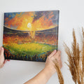 Framed canvas print of an impressionistic painting capturing a vibrant football match in a stadium at sunset