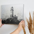 Framed canvas print of a monochrome lighthouse and seagulls on a rocky coastline