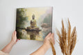 Framed canvas print of a serene golden Buddha seated by water with impressionistic background