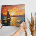 Framed canvas print of a sailboat against a vivid sunset with warm orange and blue tones