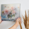 Framed canvas print of delicate dahlias in a glass vase with a soft pastel palette