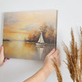 Framed canvas print of a sailboat during sunset with golden sky and water reflections