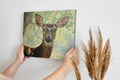 Framed canvas print of a detailed and serene deer portrait with a woodland backdrop in natural tones