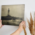 Framed canvas print of a vintage-style lighthouse on a stormy shore in sepia tones