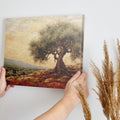 Framed canvas print of a stylised olive tree in a rustic Mediterranean landscape with warm terracotta and olive green tones