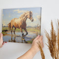 Framed canvas print of a vibrant horse wading in water with sunlit pasture and reflection