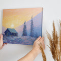 Framed canvas print of an impressionist painting with a mountain cabin at sunset