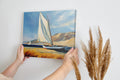 Framed canvas print of sailing boats with white sails against a backdrop of blue skies and dunes