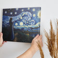 Framed canvas print of a woman in a blue dress gazing at a starry night sky with swirling patterns over a village